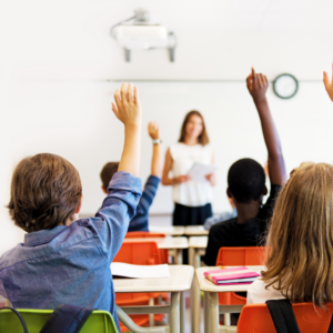 Children raising hands in a classroom. 