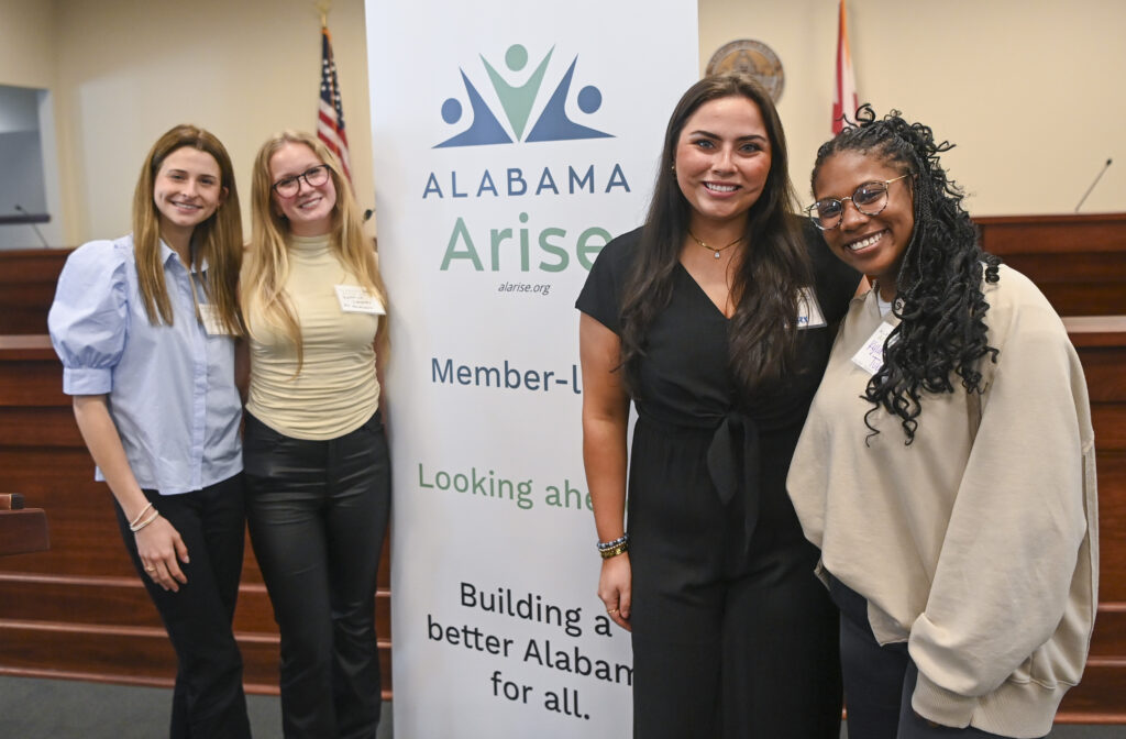 Four women stand posing for a picture while smiling.