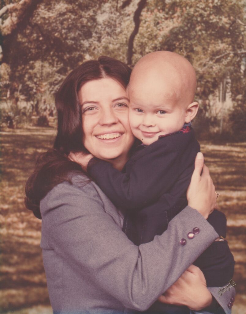 A photo with film quality from the 1980's in which a mother is holding her son. 